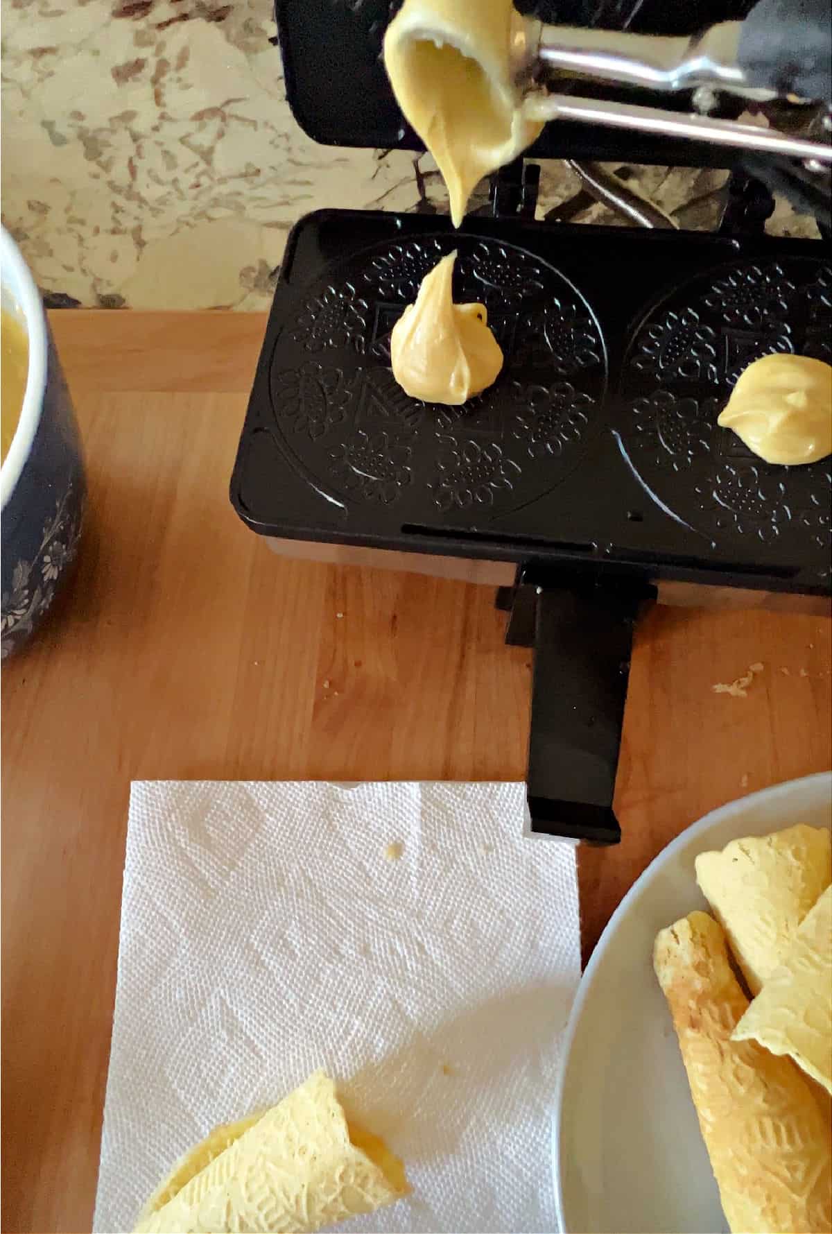 scoop of dough put into the krumkaker baker.