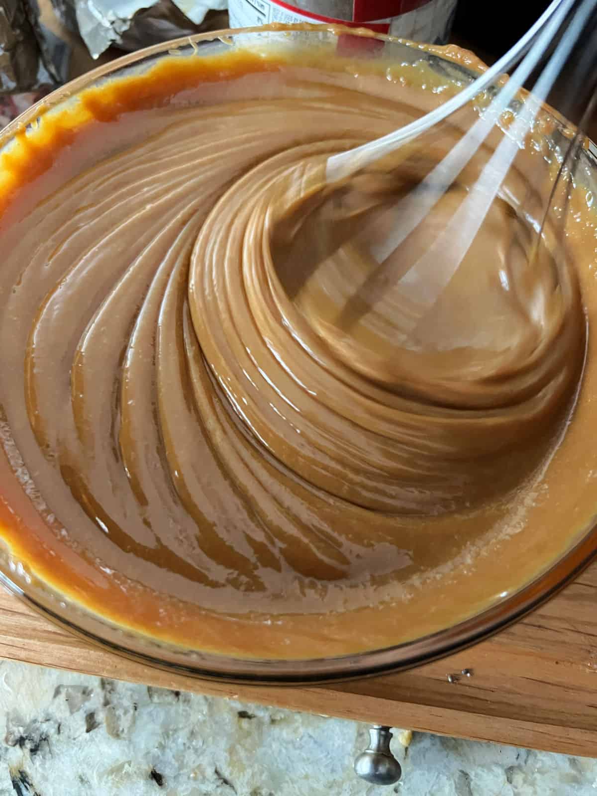 caramel sauce in a bowl being stirred with a whisk.