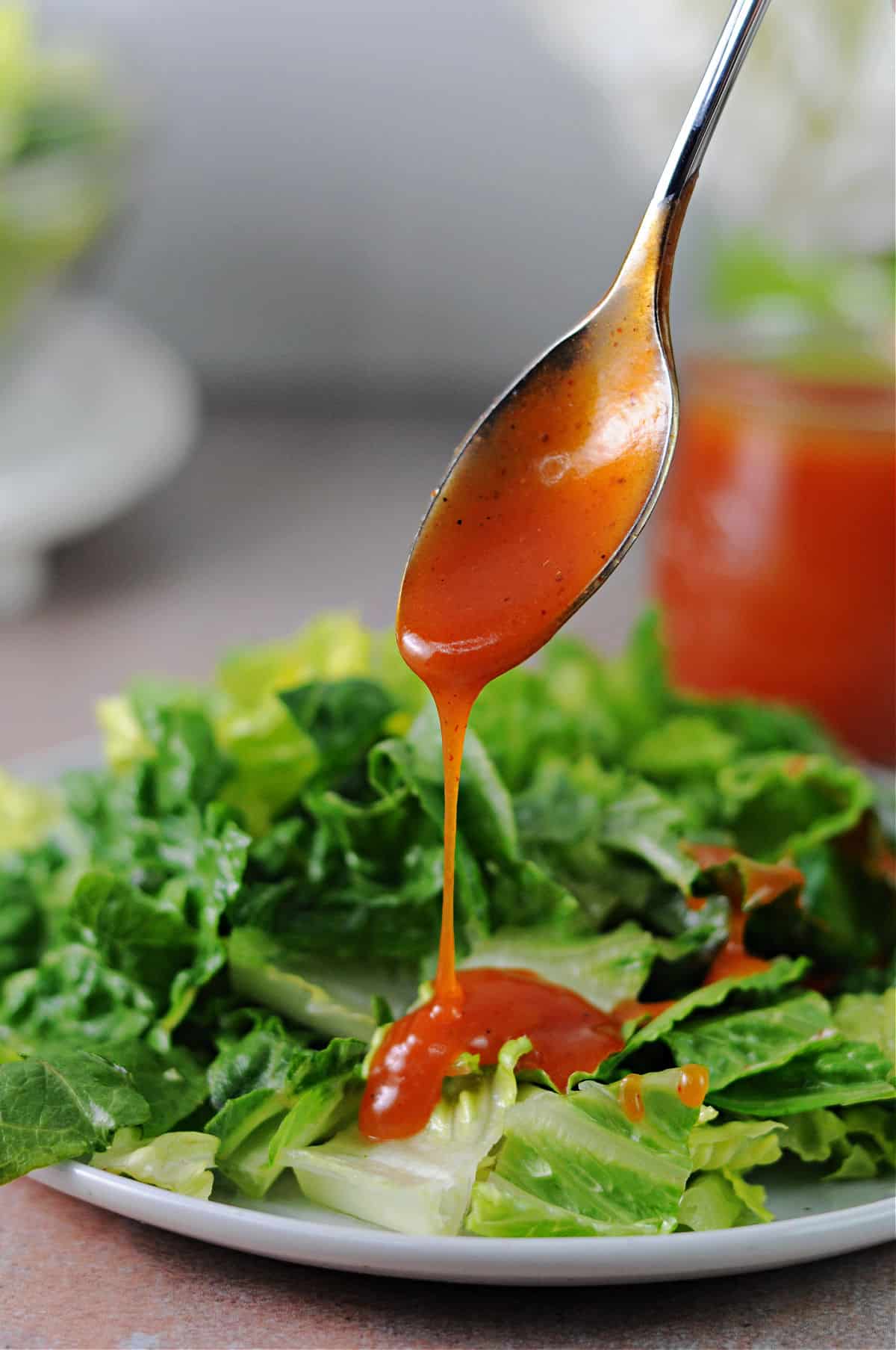 spoonful of sweet catalina dressing pouring onto a lettuce salad.