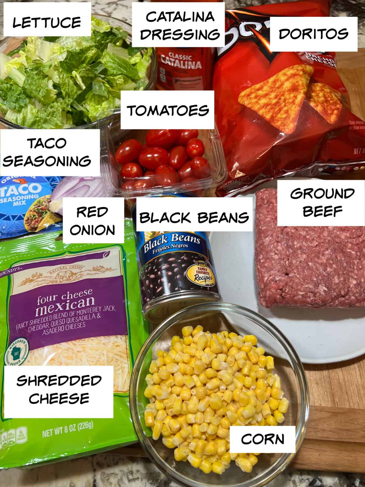 inngredients: lettuce, dressing, tortilla chips, tomatoes, ground beef, taco seasoning, red onion, black beans, corn, shredded cheese.