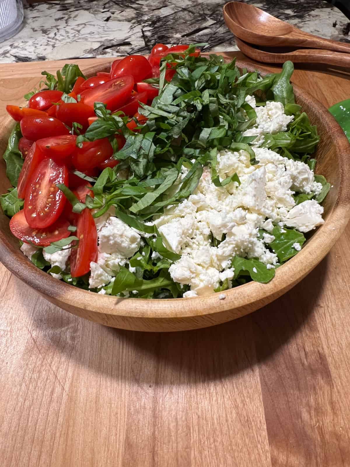 undressed salad ingredients in a wooden bowl.