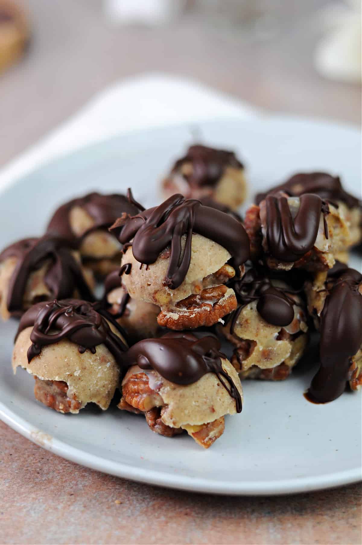 chocolate drizzled keto pecan clusters on a small plate.