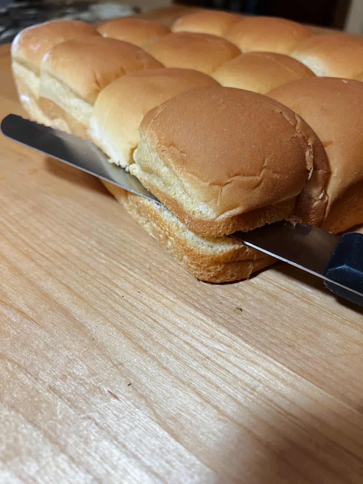 knife cutting lengthwise into the pack of dinner rolls.