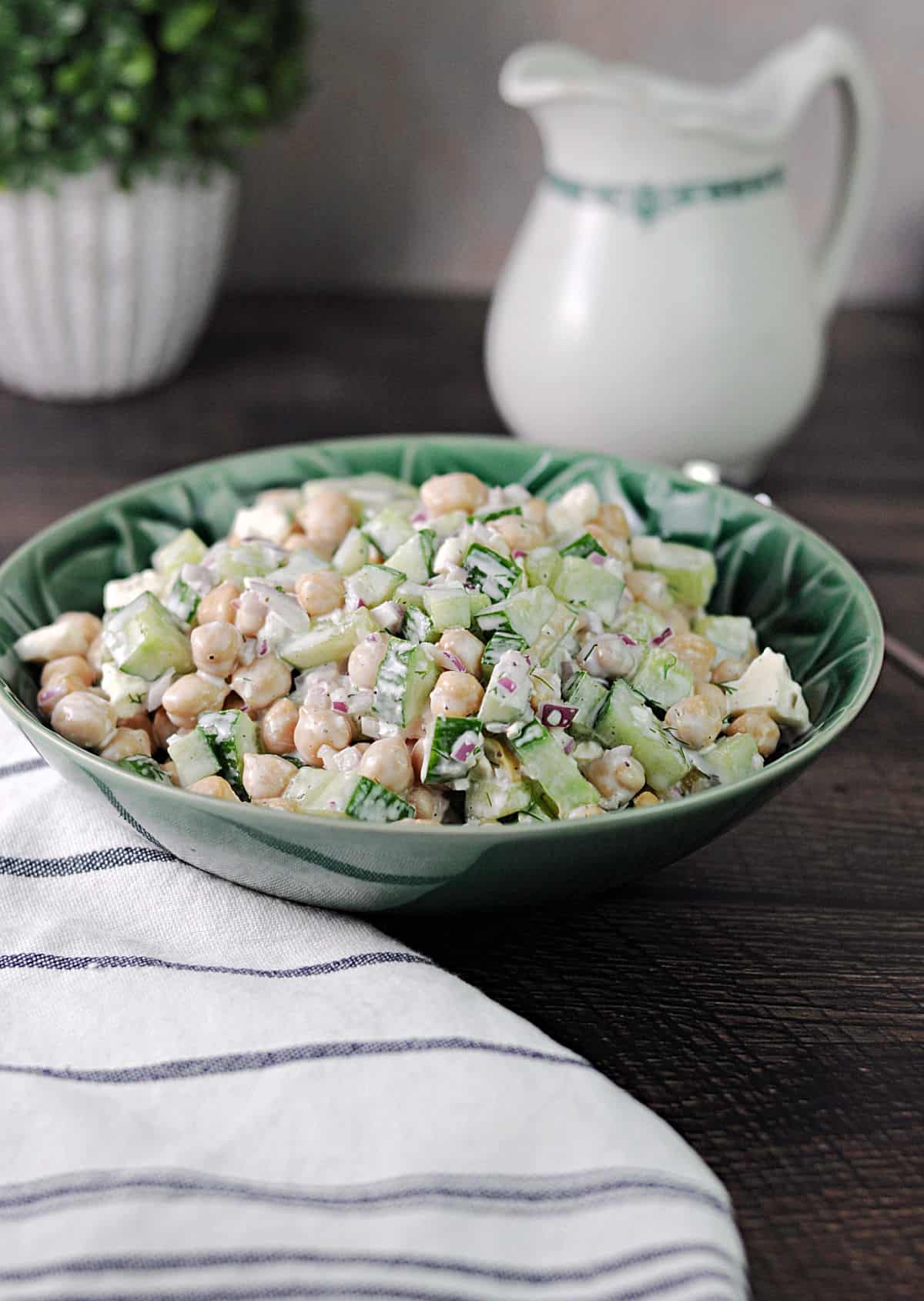 A green serving bowl of cucumber chickpea salad with feta.