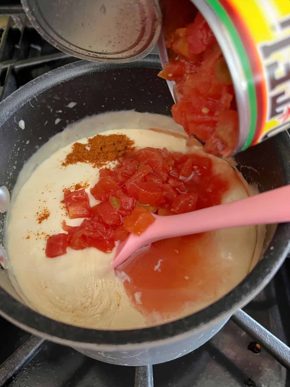 adding cayenne and diced tomatoes to saucepan.