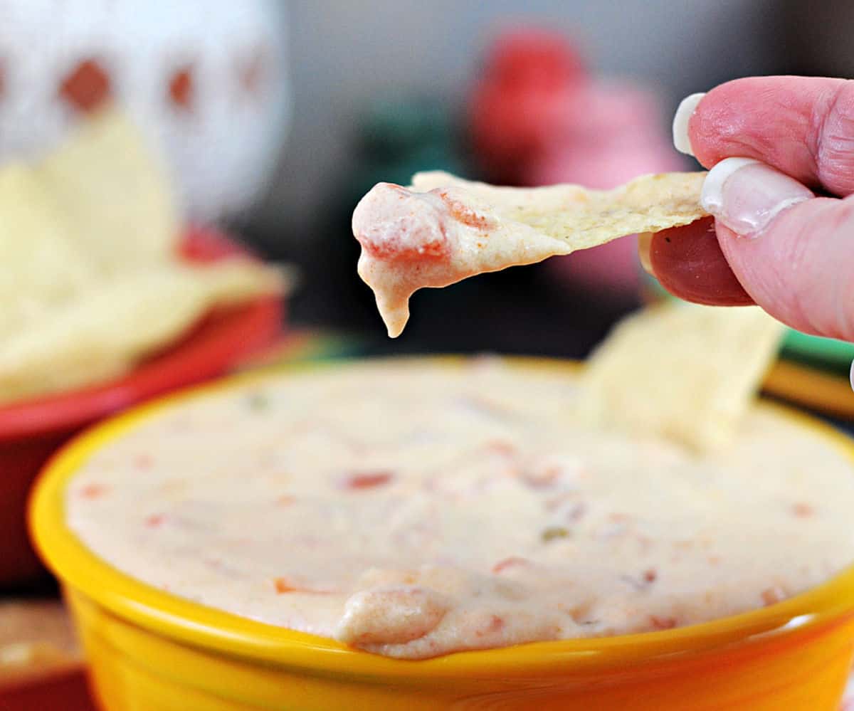 hand holding a chip dipped in Monterey Jack Queso dip.