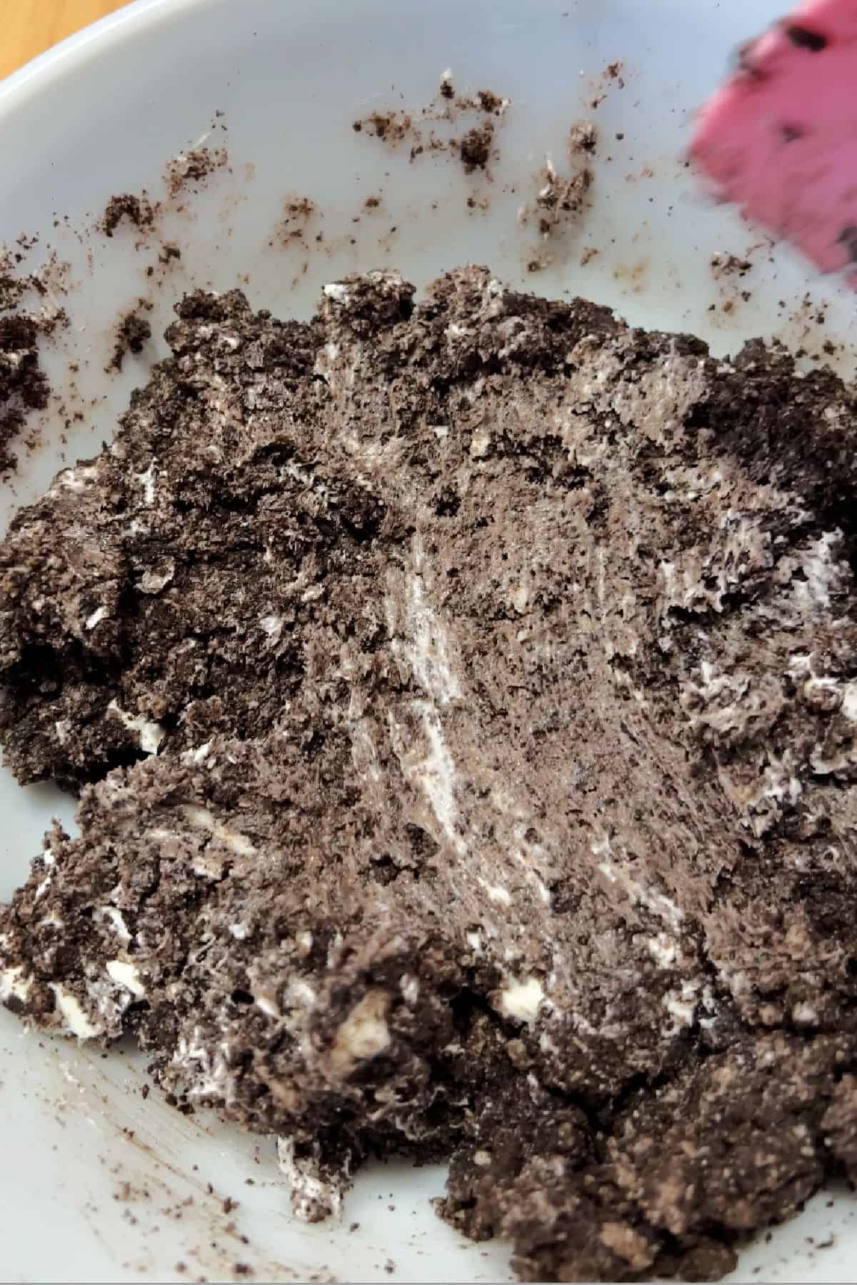 mixing crushed Oreos and cream cheese in a bowl.