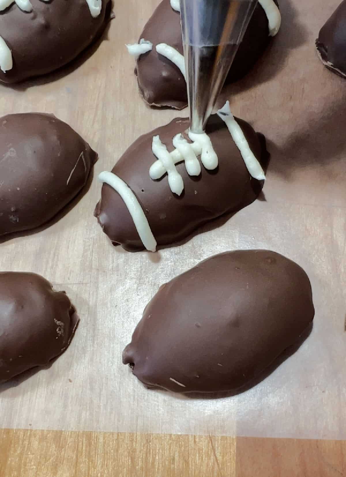 piping white frosting onto the football Oreo truffle to resemble markings on a football.