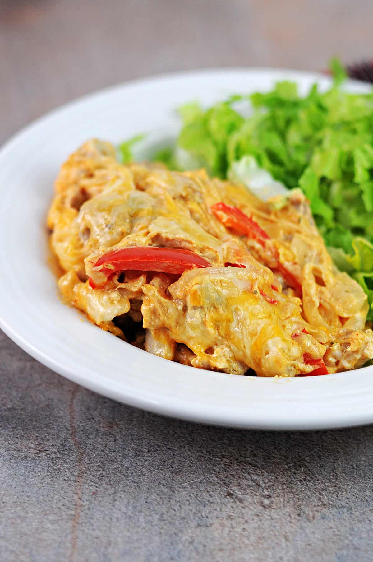 a bowl with a serving of chicken fajita casserole, plus some salad.