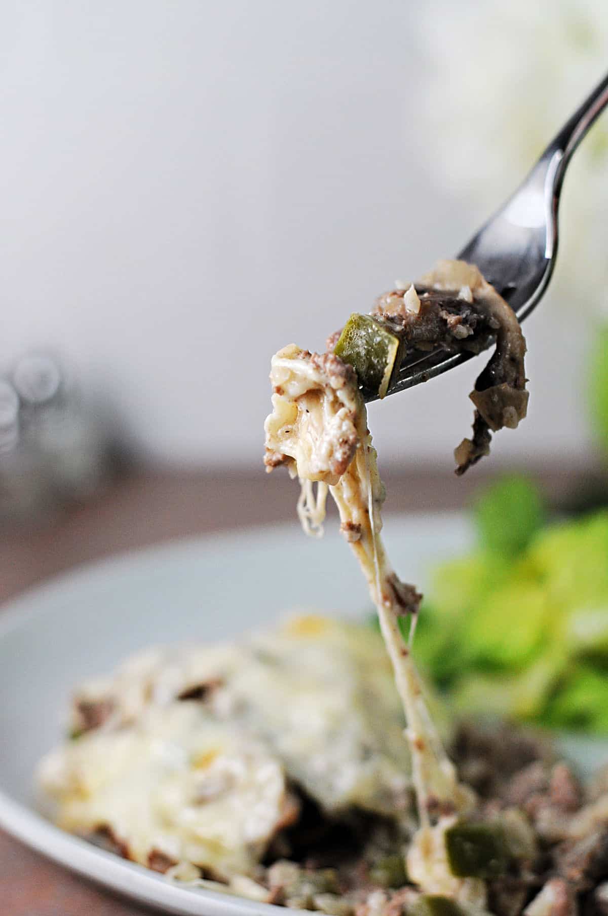 fork of casserole with a trail of melted cheese pulling from the plate.