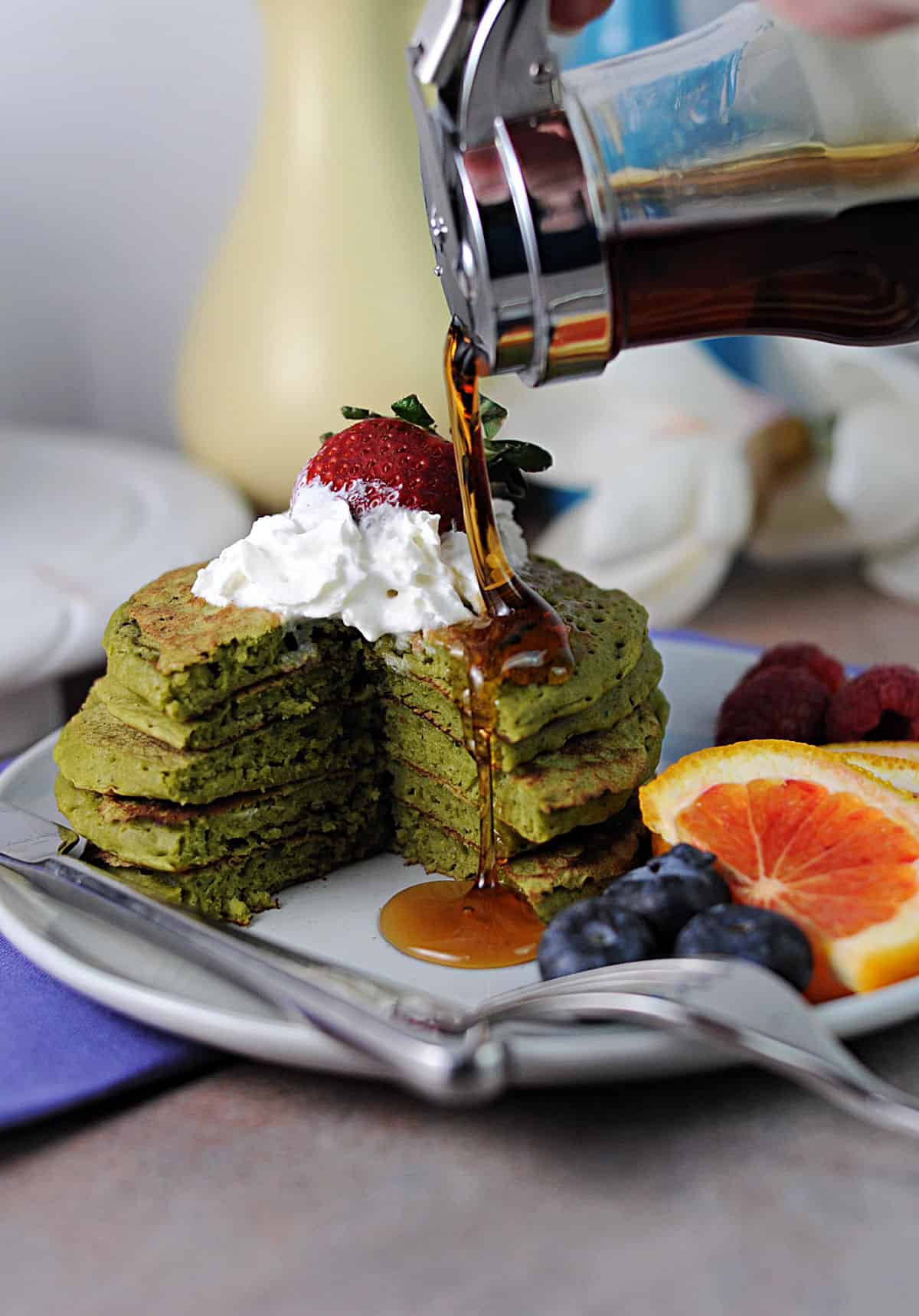 syrup pouring over a stack of matcha pancakes.