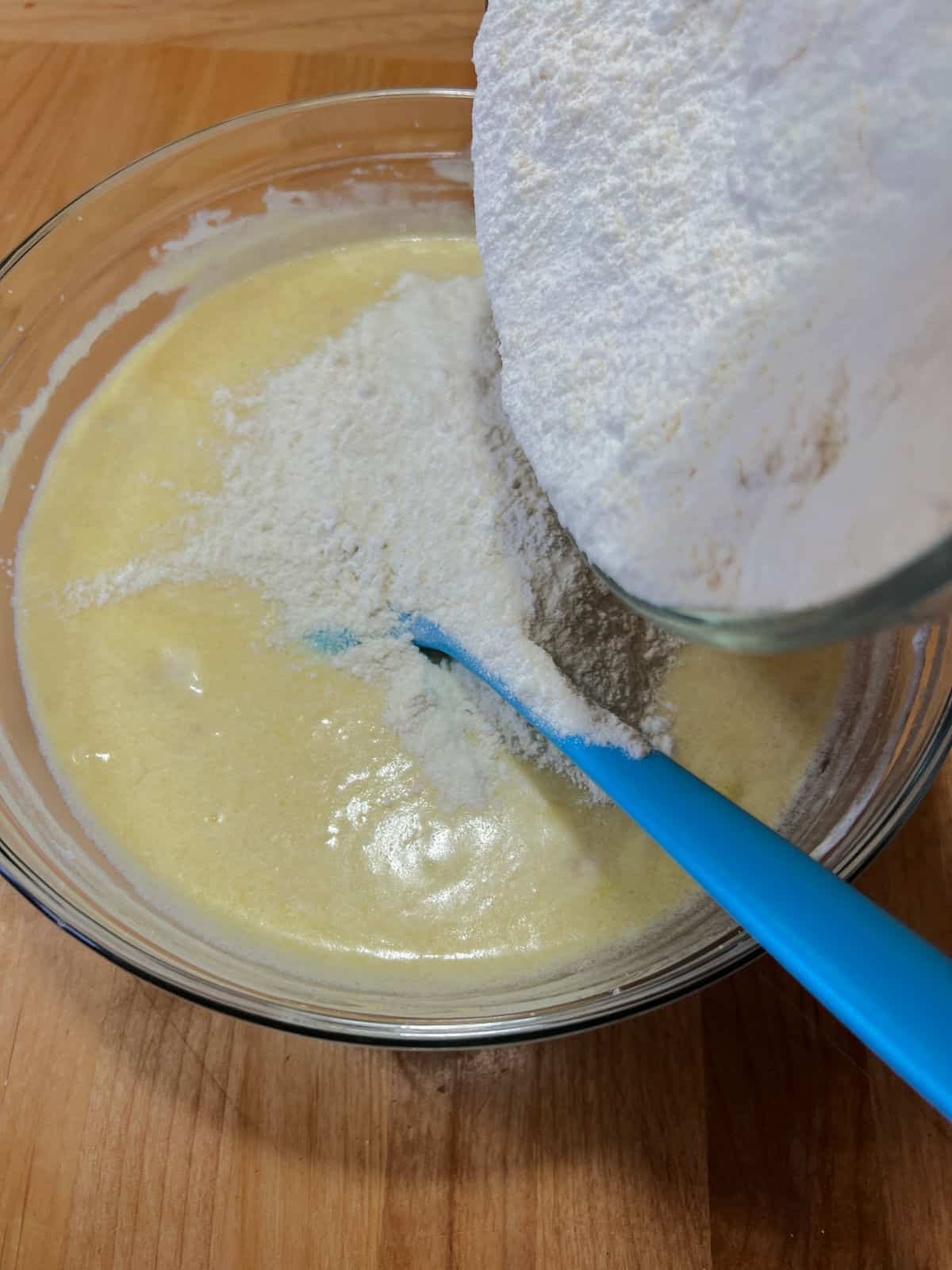 adding dry ingredients to the bowl of wet ingredients.