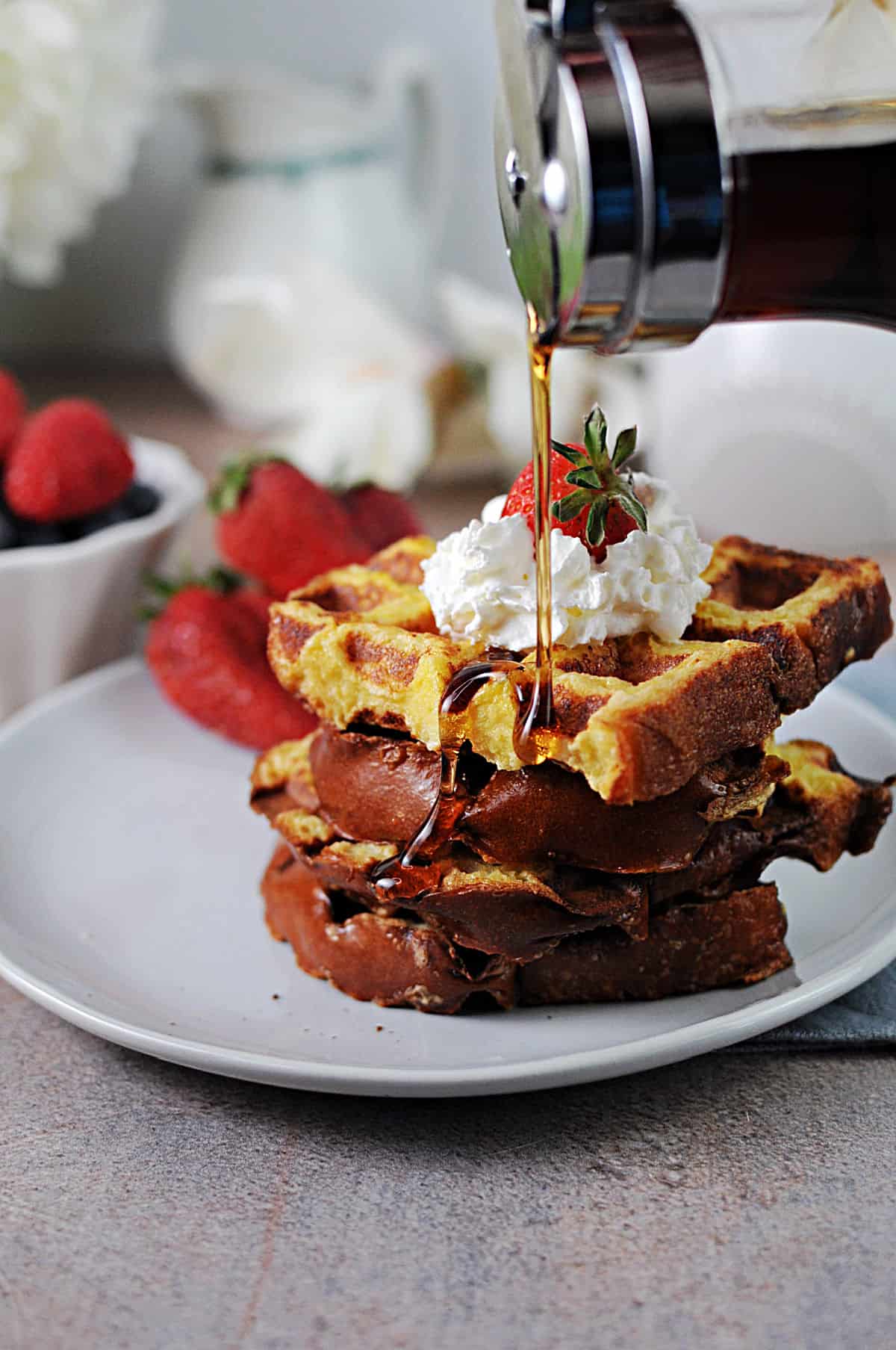 stack of french toast waffles getting syrup poured on top.