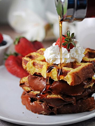 Waffle iron French toast getting drizzled with syrup.