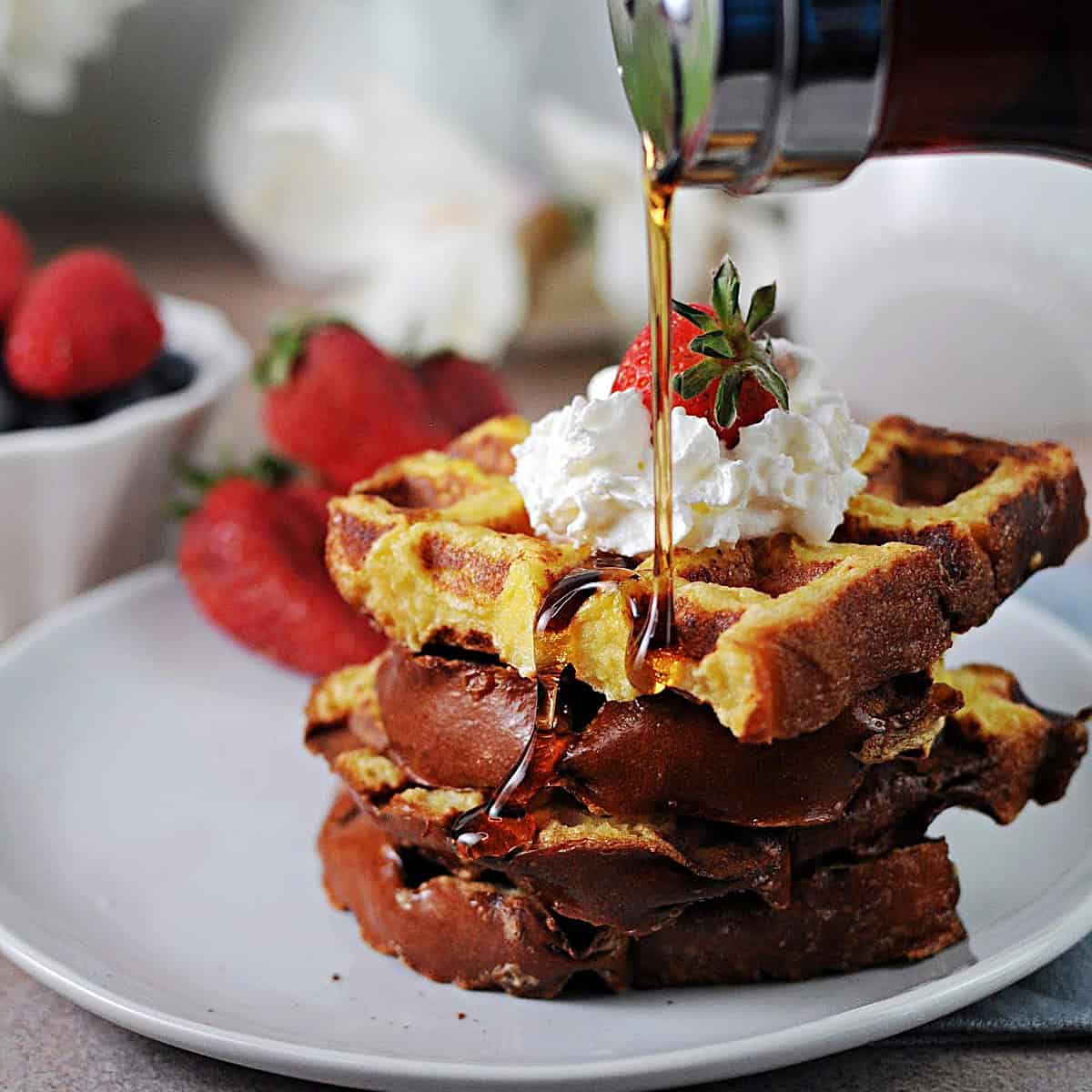 Waffle iron French toast getting drizzled with syrup.