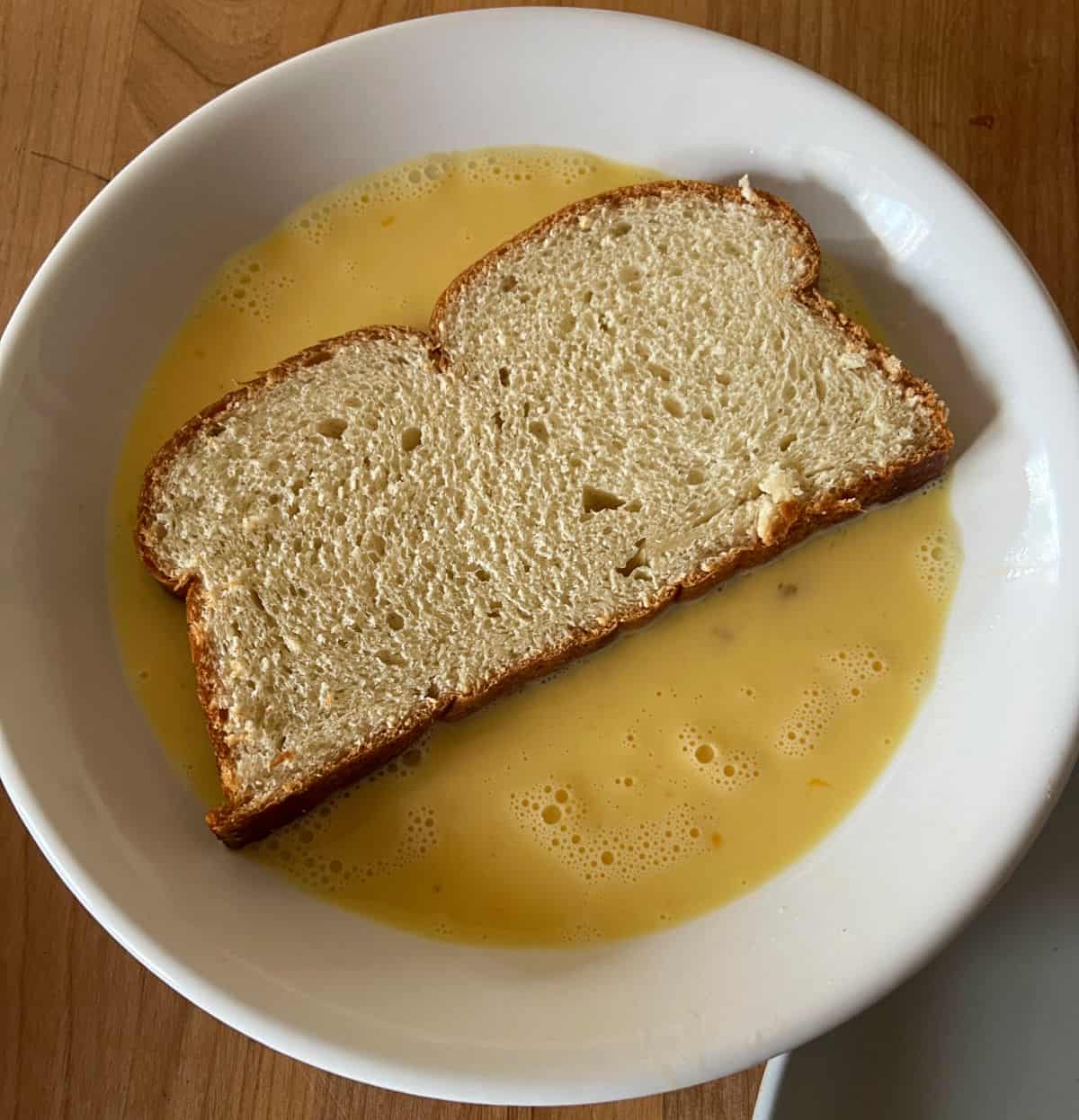 miche bread placed in egg mixture.