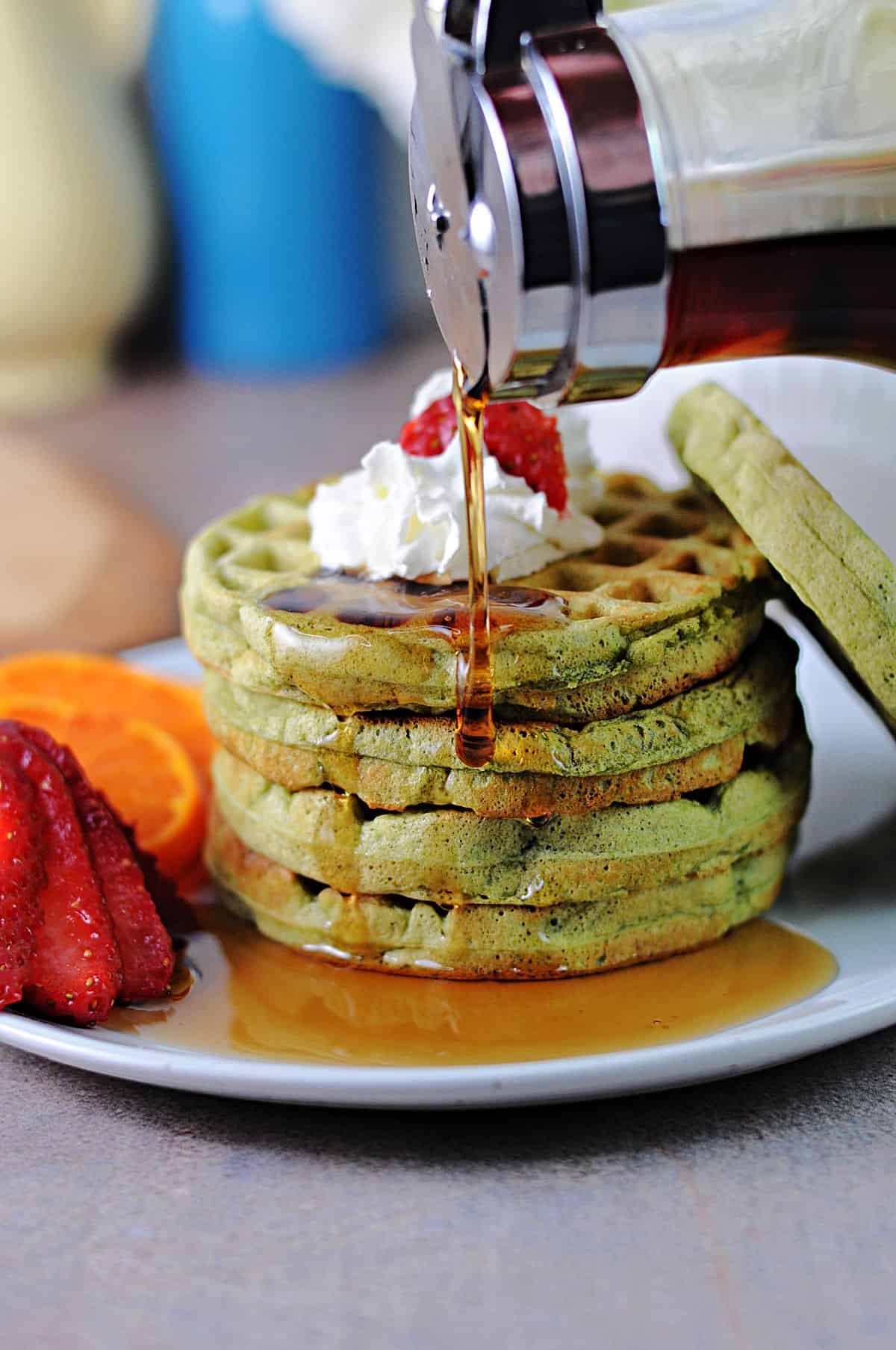 stack of matcha waffles with syrup pouring onto the edge.