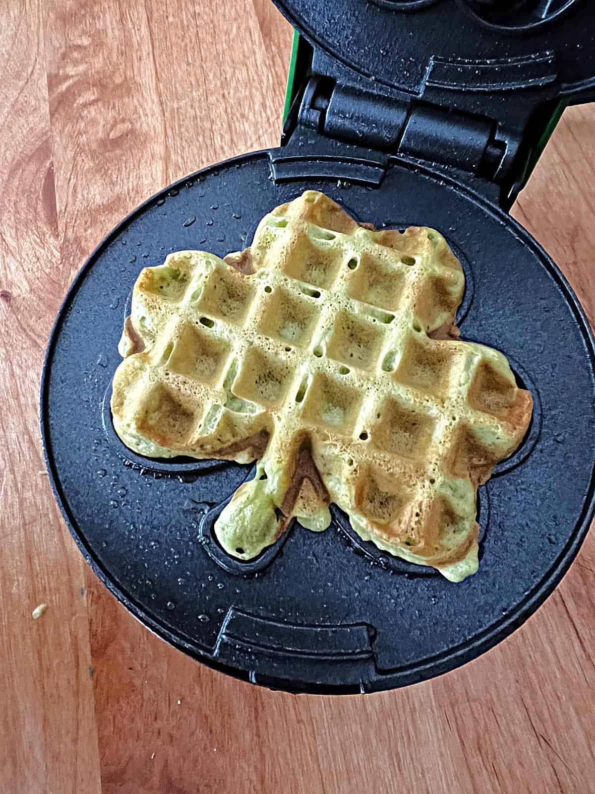green mini waffle in a shamrock shaped waffle iron. 
