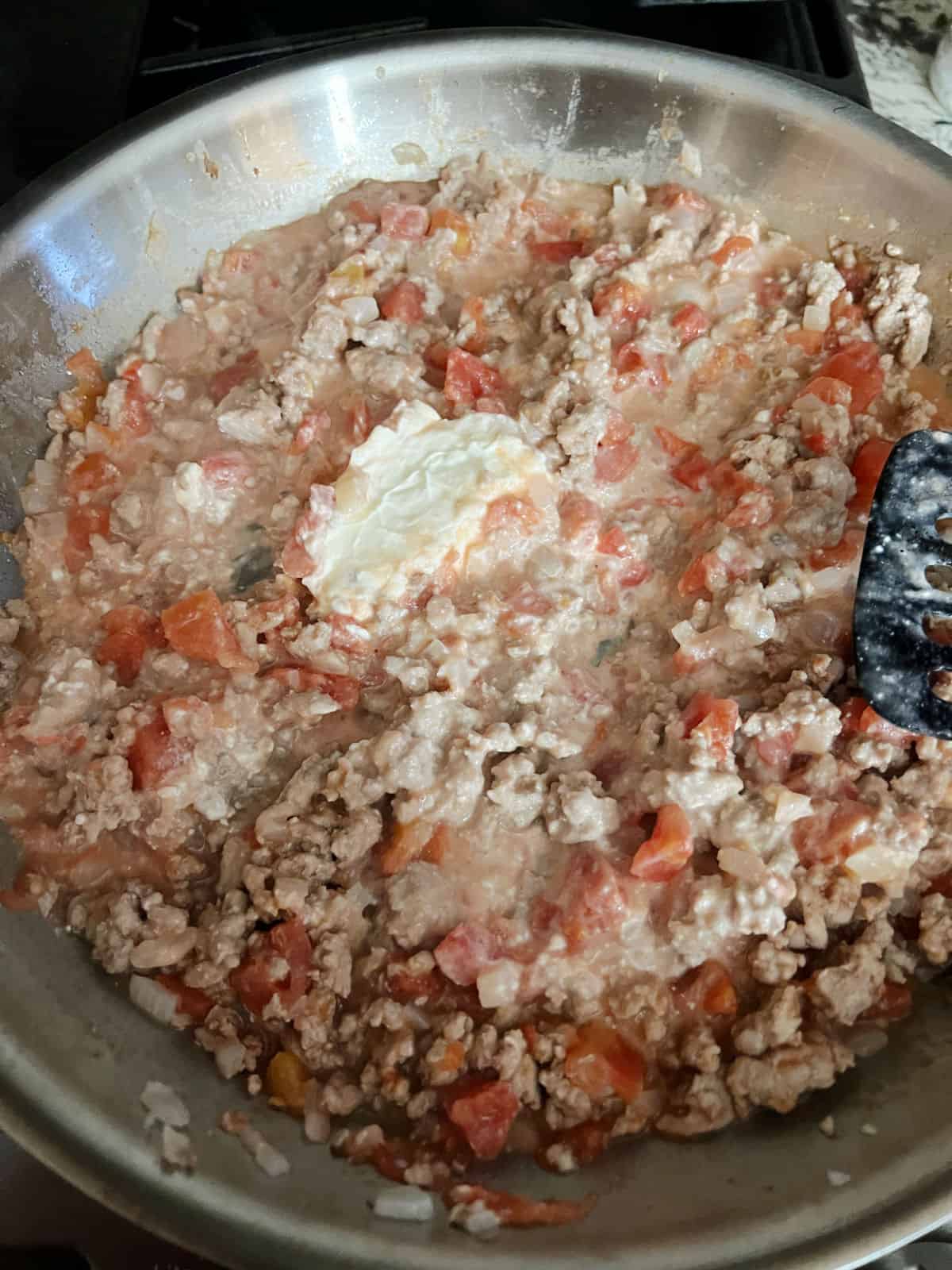 cream cheese melting in the skillet of cooked turkey and diced tomato mixture.