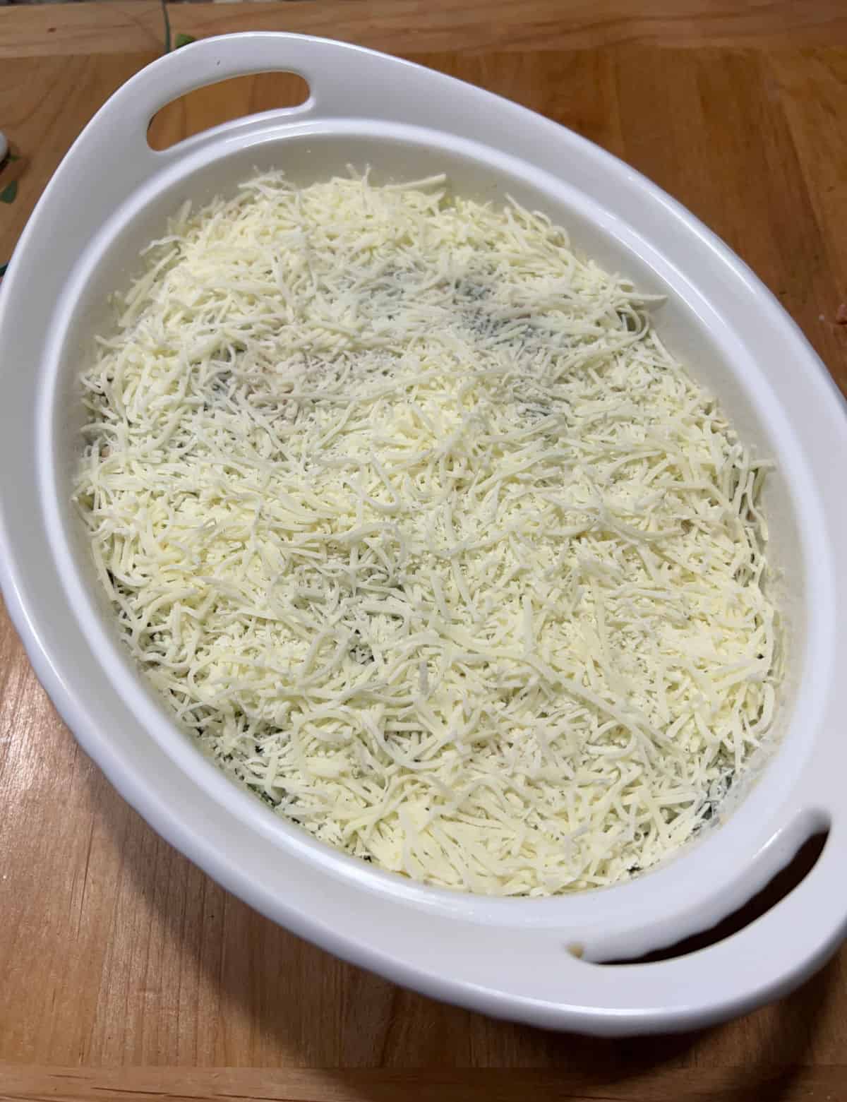 mixture in casserole dish and the top is sprinkled with shredded cheese.