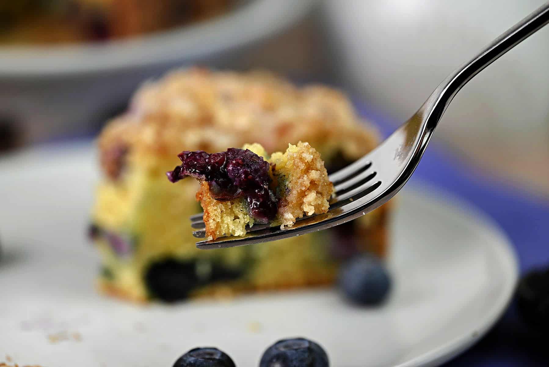 a fork holding a bite of blueberry sour cream coffee cake.