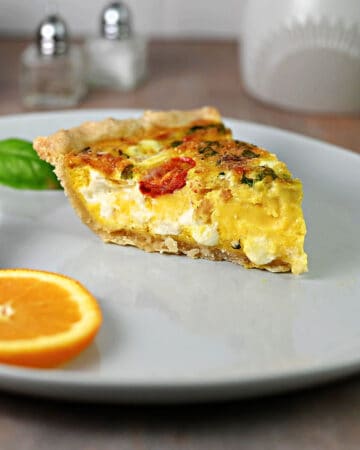 Slice of Caprese quiche on a plate, ready to eat.