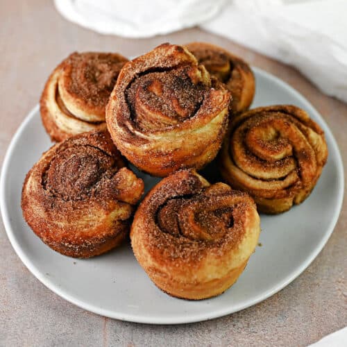 6 cinnamon roll puff pastry cruffins stacked on a small plate.
