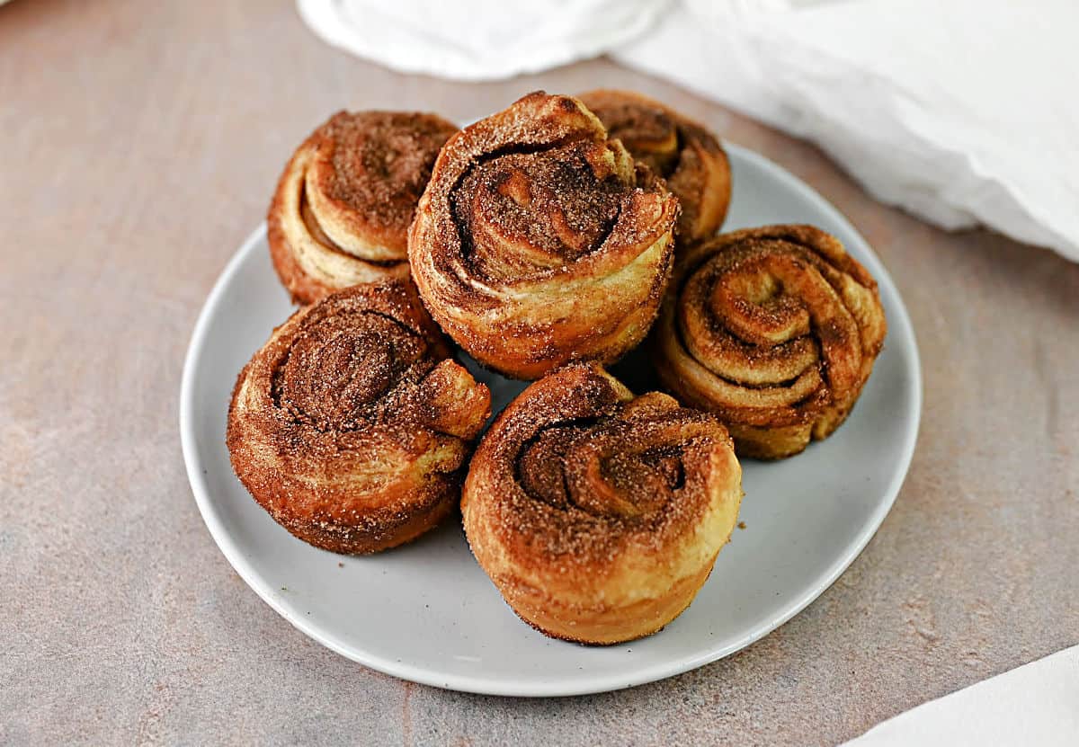 A stack of 6 cinnamon puff pastry cruffins on a small plate.