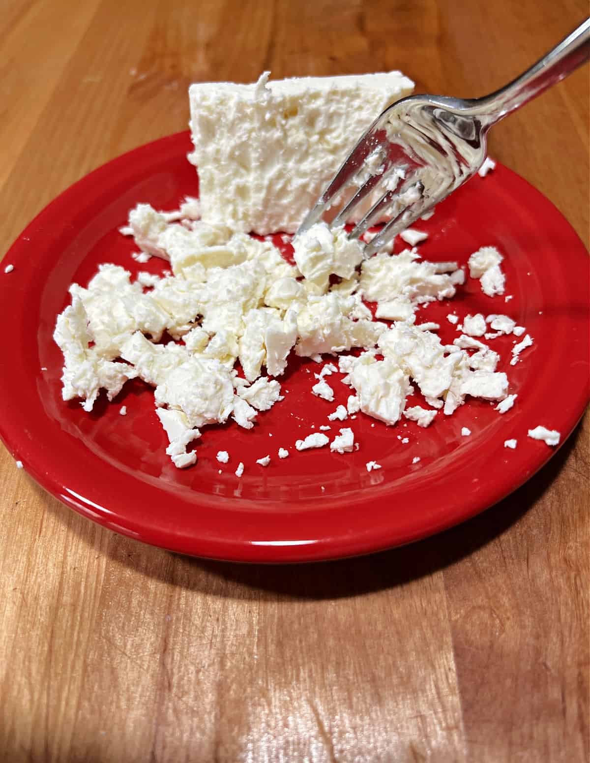 Breaking up a block of feta cheese with a fork.