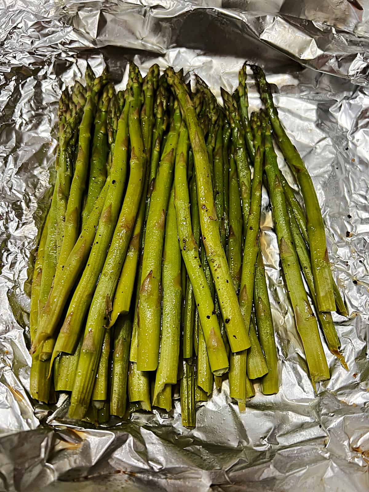 Open foil packet of grilled asparagus.