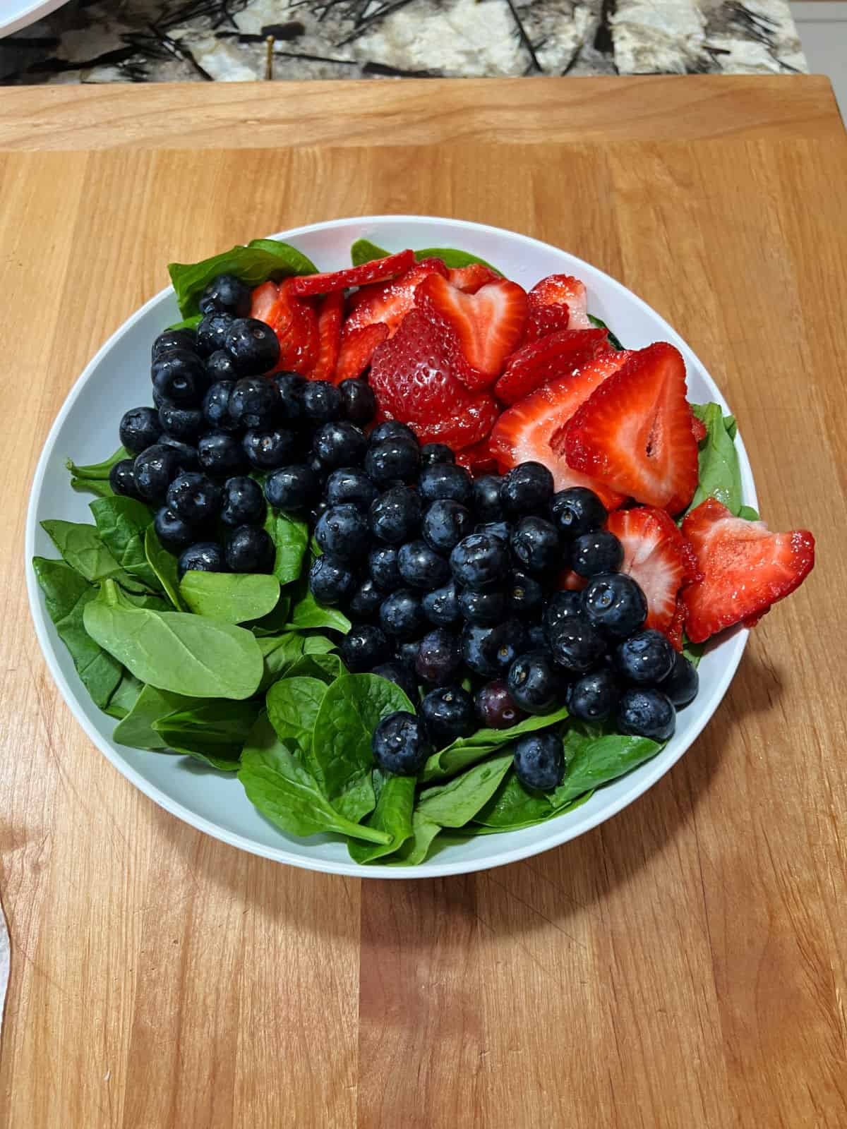 Spinach, blueberries, and strawberries in a bowl.