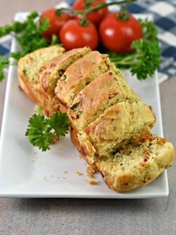 Sliced mini loaf of sun dried tomato bread on a serving platter.