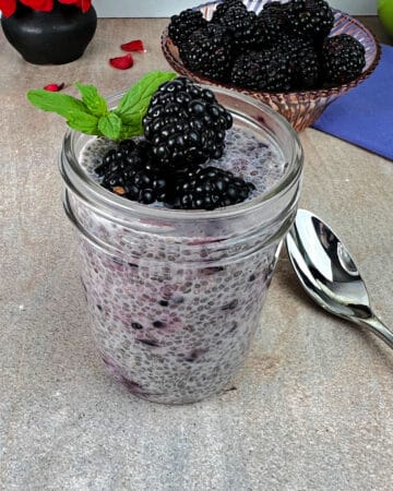 Blackberry Chia Seed pudding in a samll jar, garnished with fresh berries and a sprig of mint.