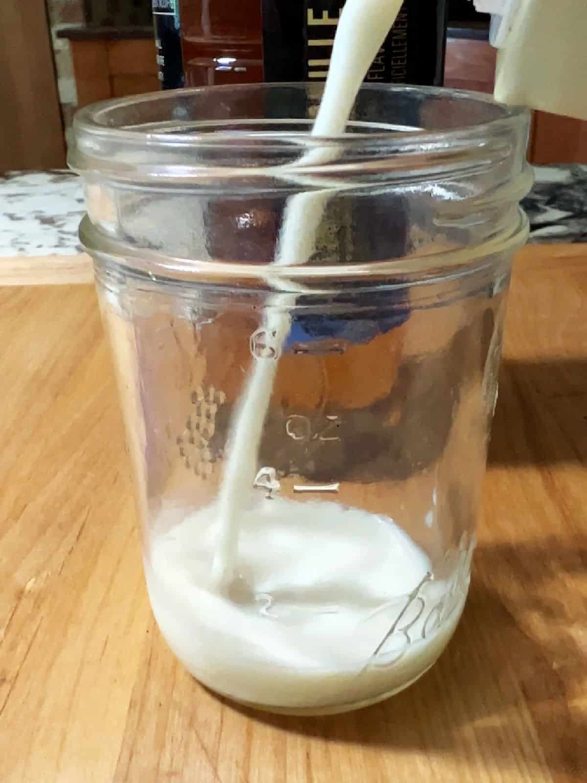 Adding almond milk to the jar.