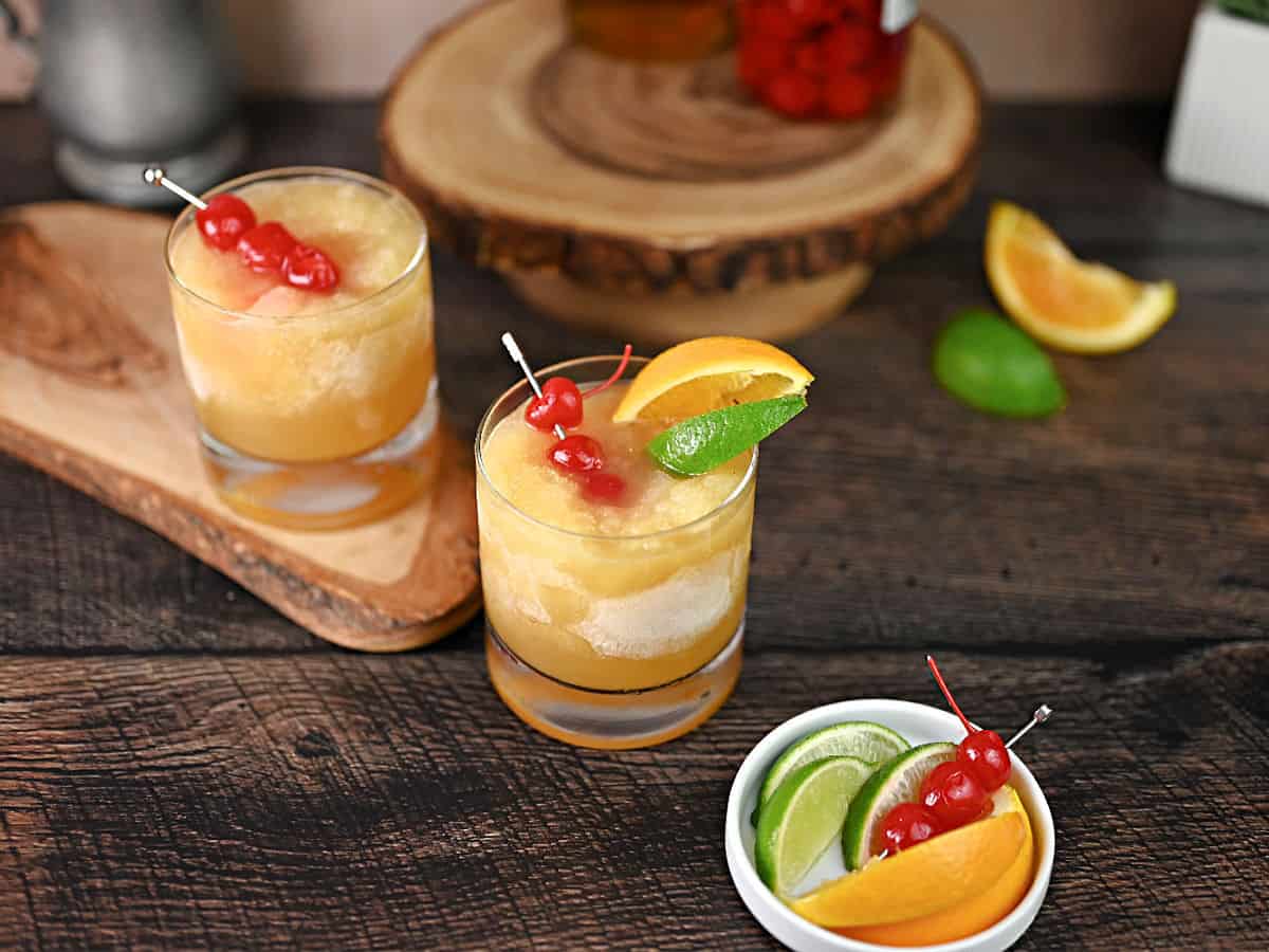 2 glasses of brandy slush garnished with citrus slices and cherries.