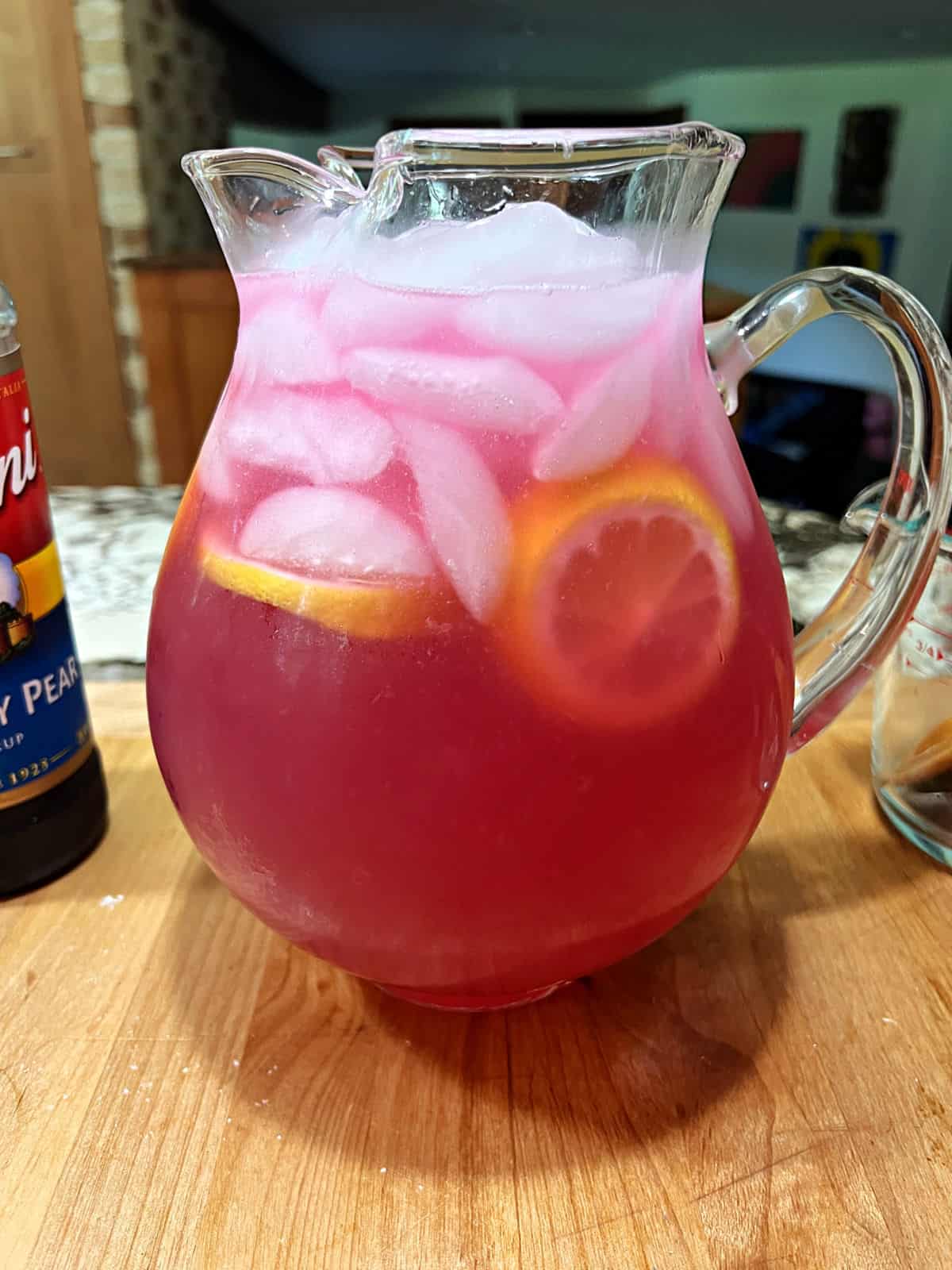 Pitcher of pink lemonade filled with ice and lemon slices.