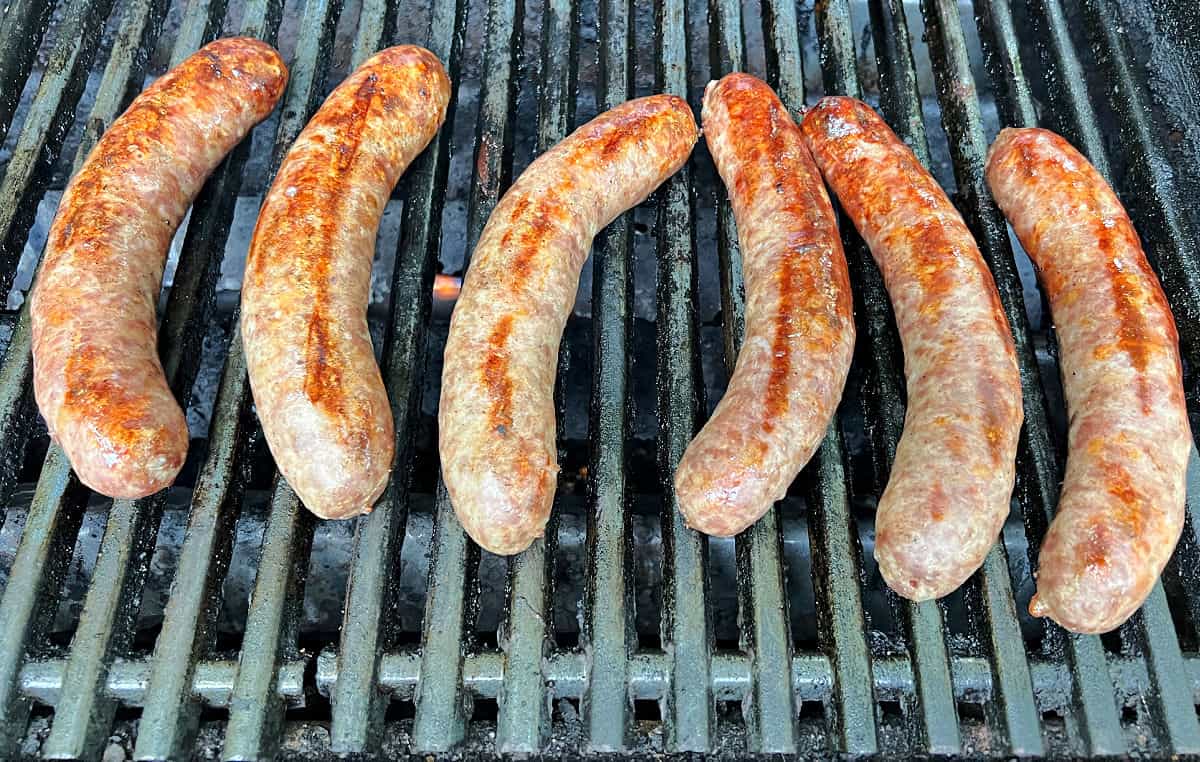 Bratwurst browning on a gas grill.