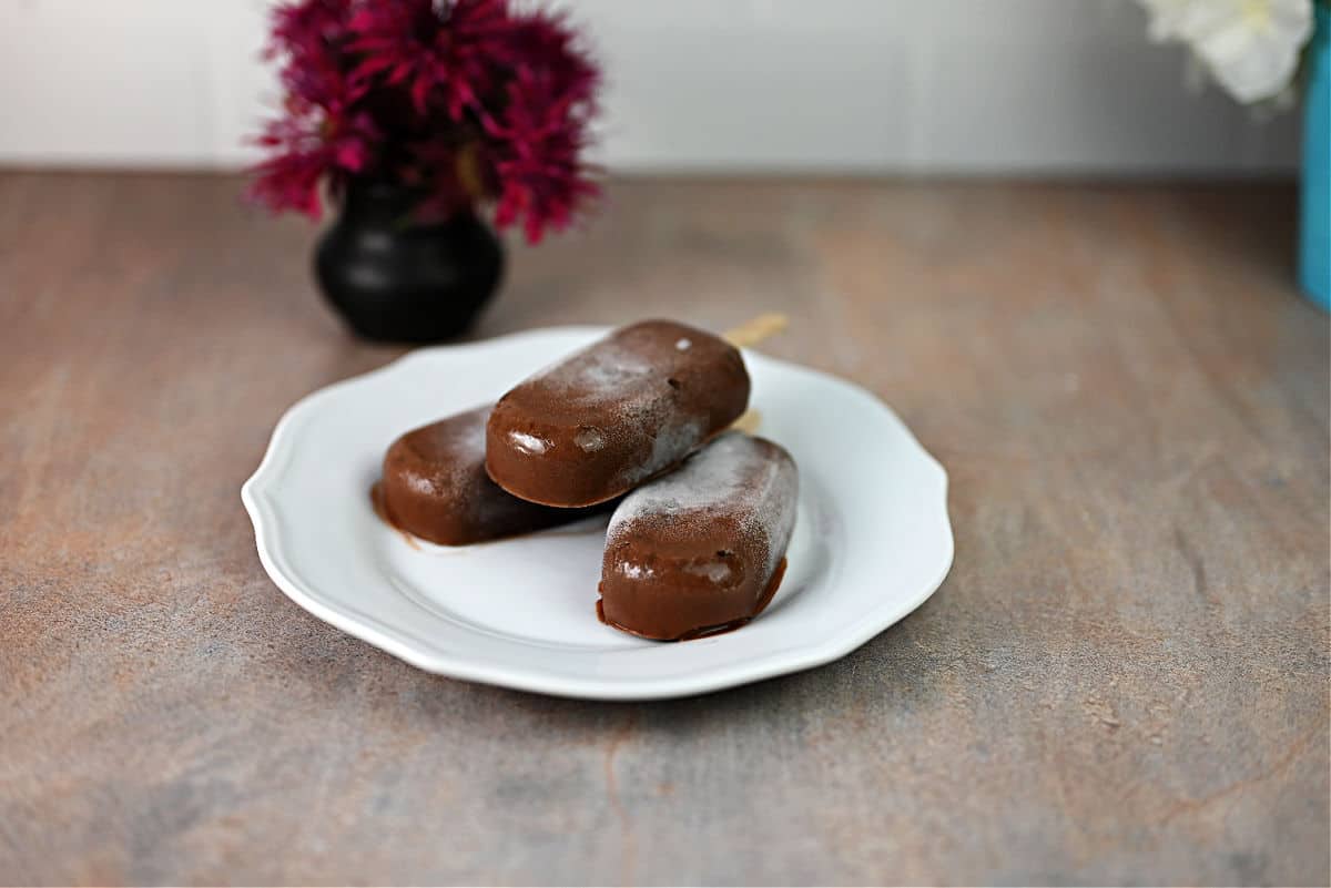 3 homemade fudgesicles thawing on a plate.