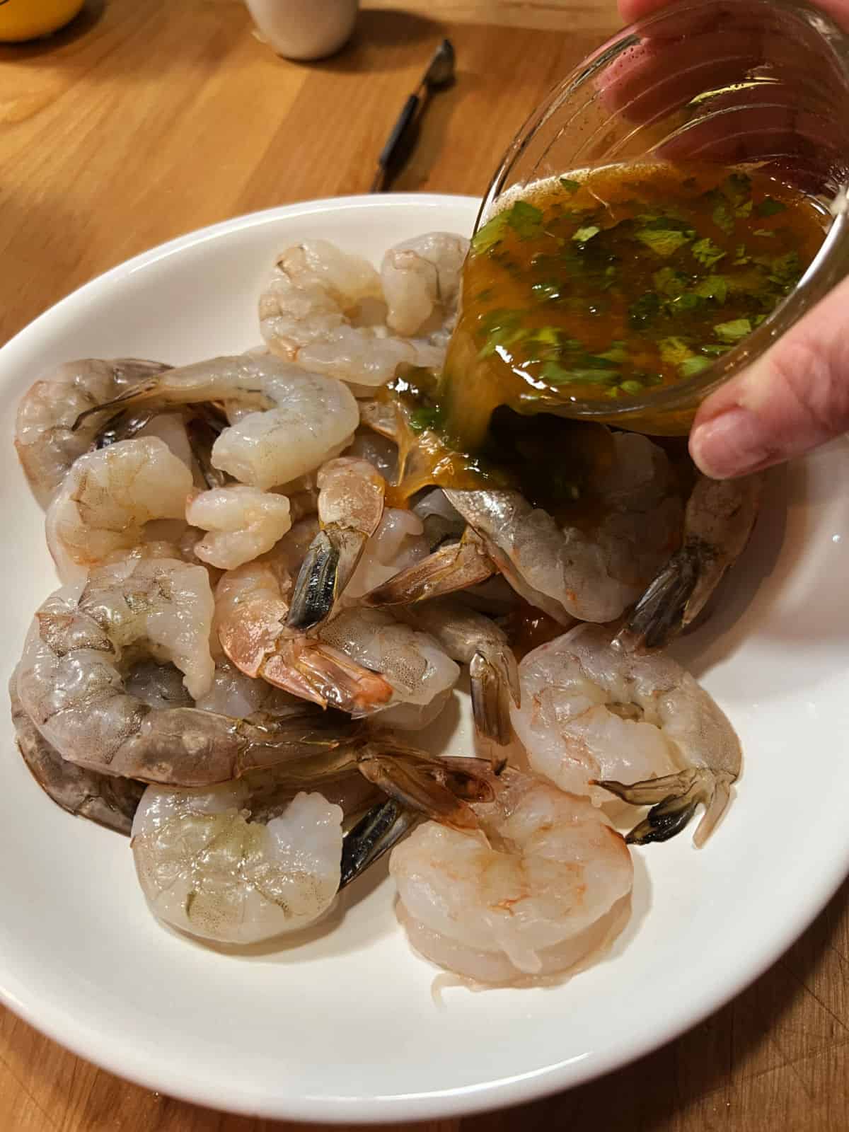 Pouring marinade over the shrimp.