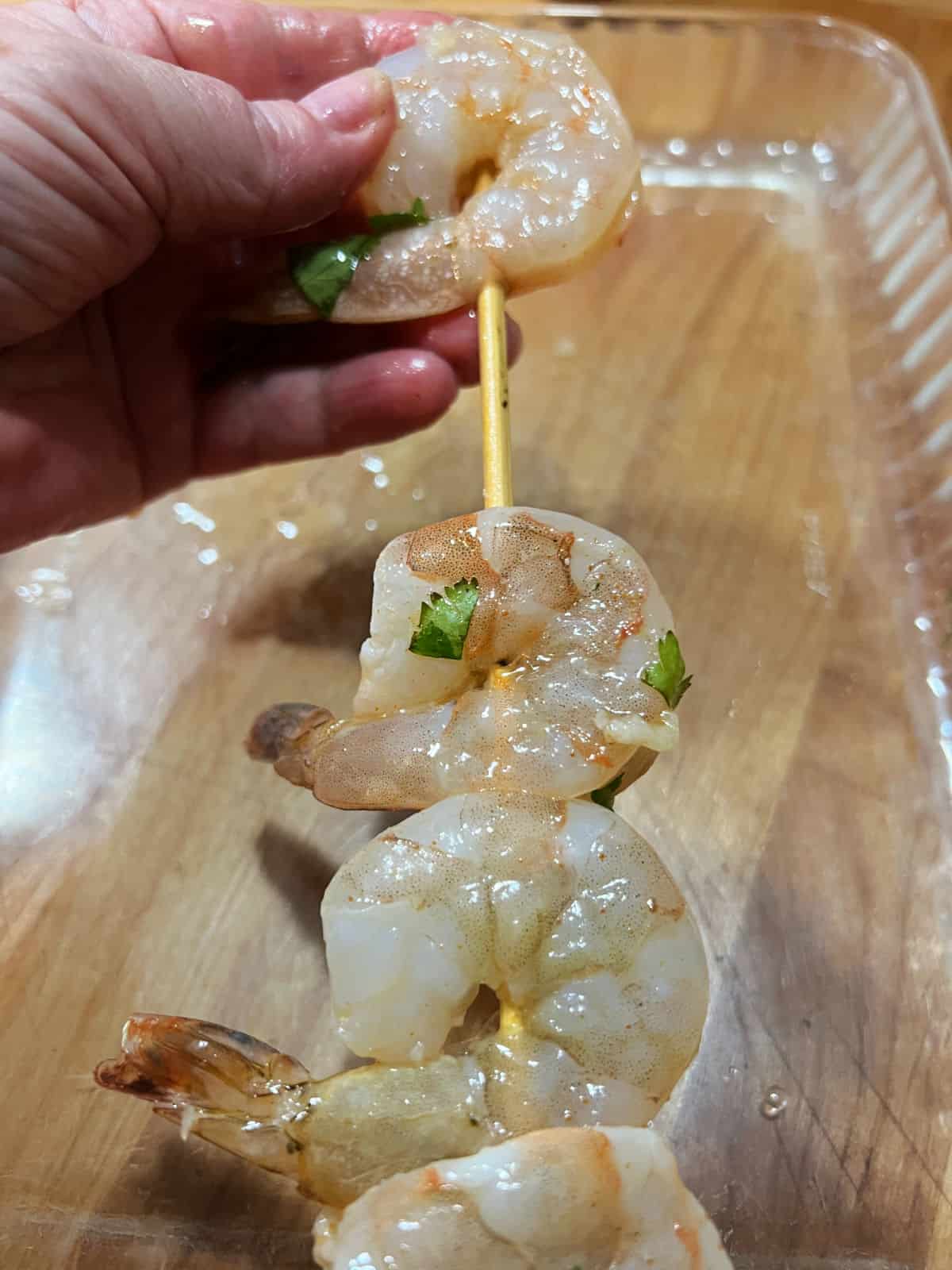 Threading shrimp onto a bamboo skewer.