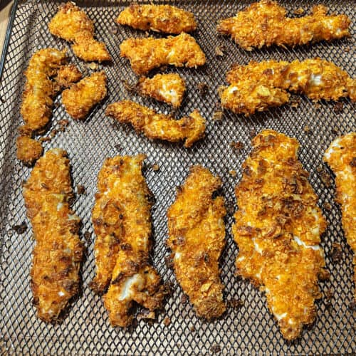 Cooked Dorito coated chicken tenders in an air fryer basket.
