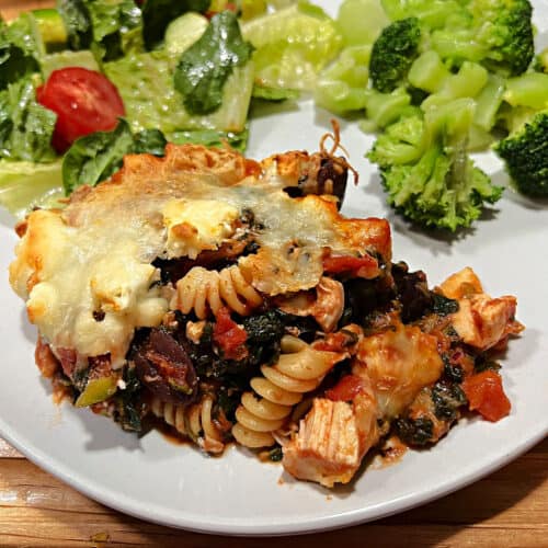 Greek Chicken Casserole on a plate with salad.