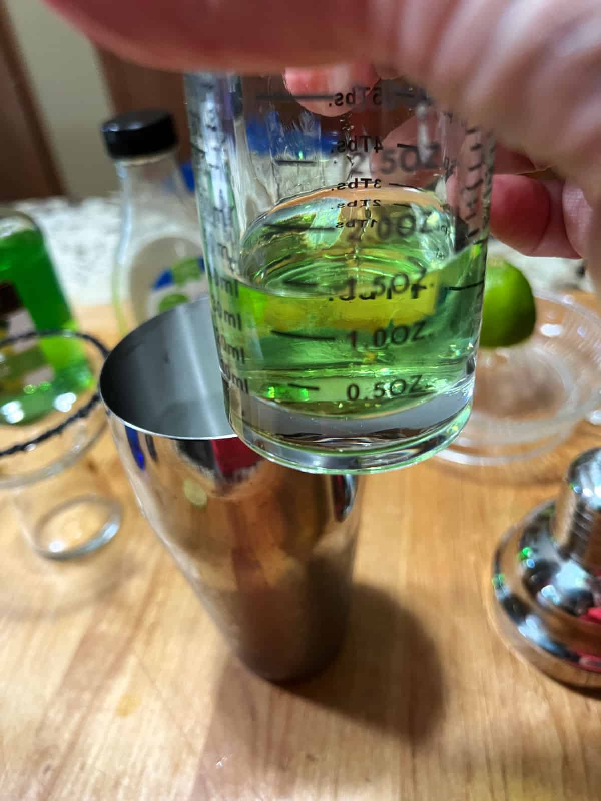 Pouring the schnapps into the cocktail shaker.