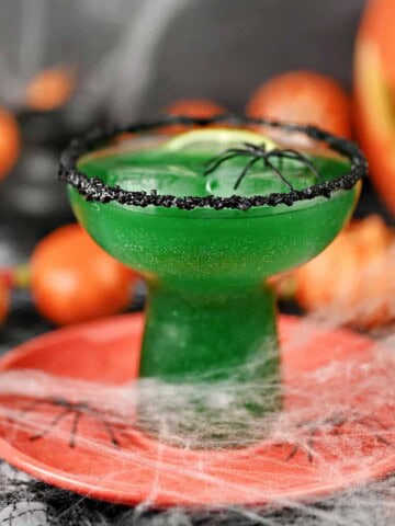 Poison Apple Margarita surrounded by spider webs and spiders.
