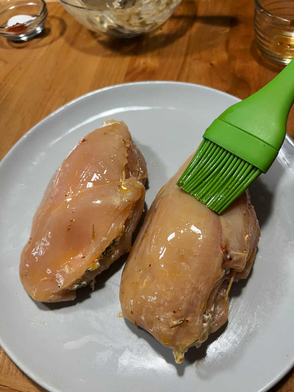 Brushing the chicken breasts with oil.