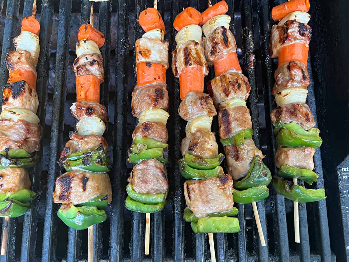 sweet and sour pork kabobs cooking on the grill.