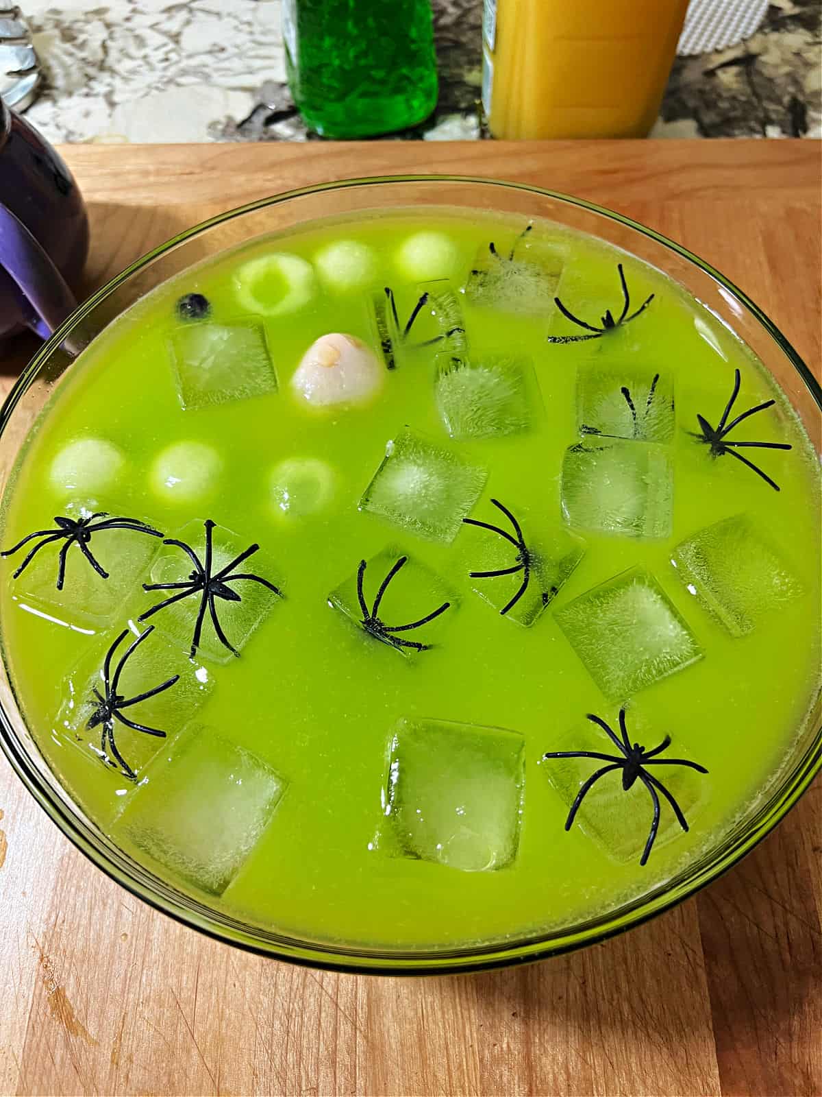 Punch bowl of witches brew cocktail showing floating ice, spiders, and eyeballs.