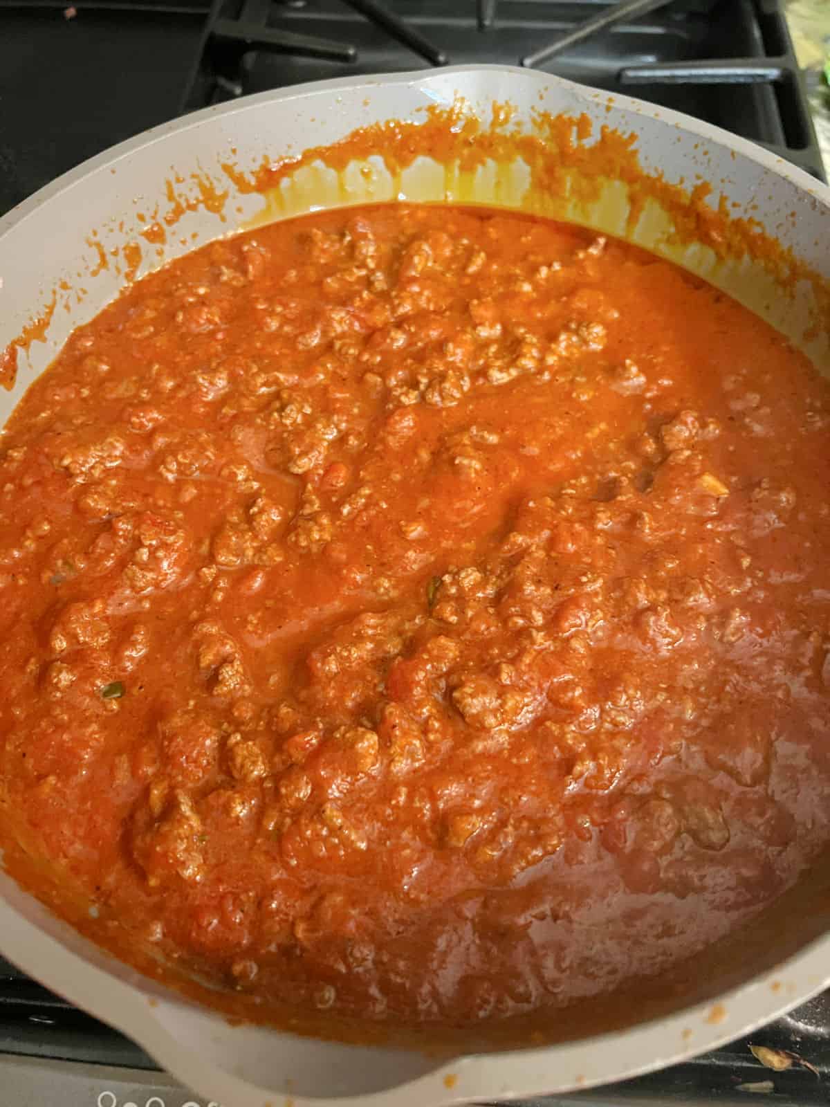 Meat and sauce simmering in a pan.