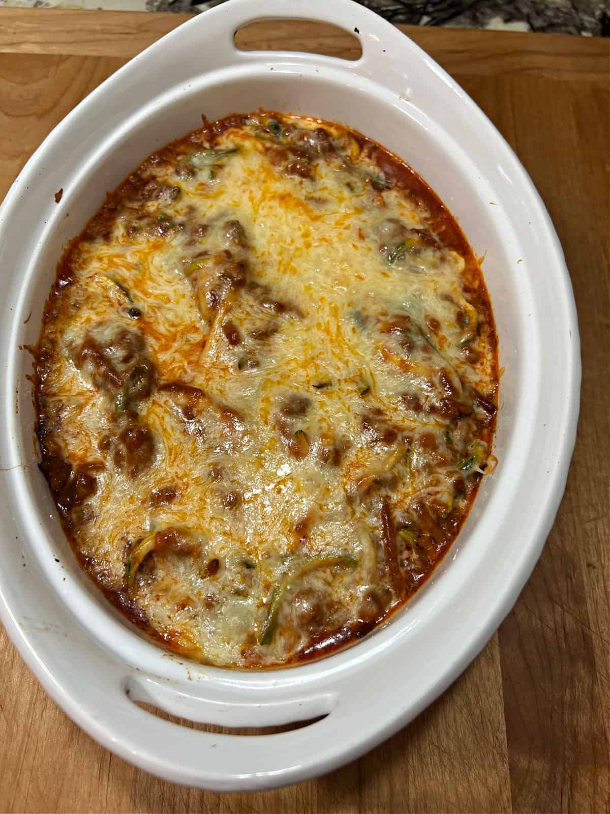 Baked spaghetti casserole showing melted cheese on top.
