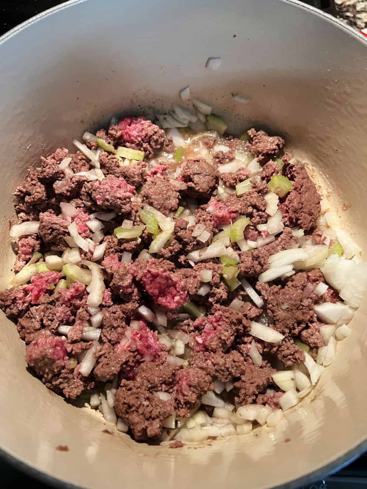 ground beef browning in the pot with onion and celery.